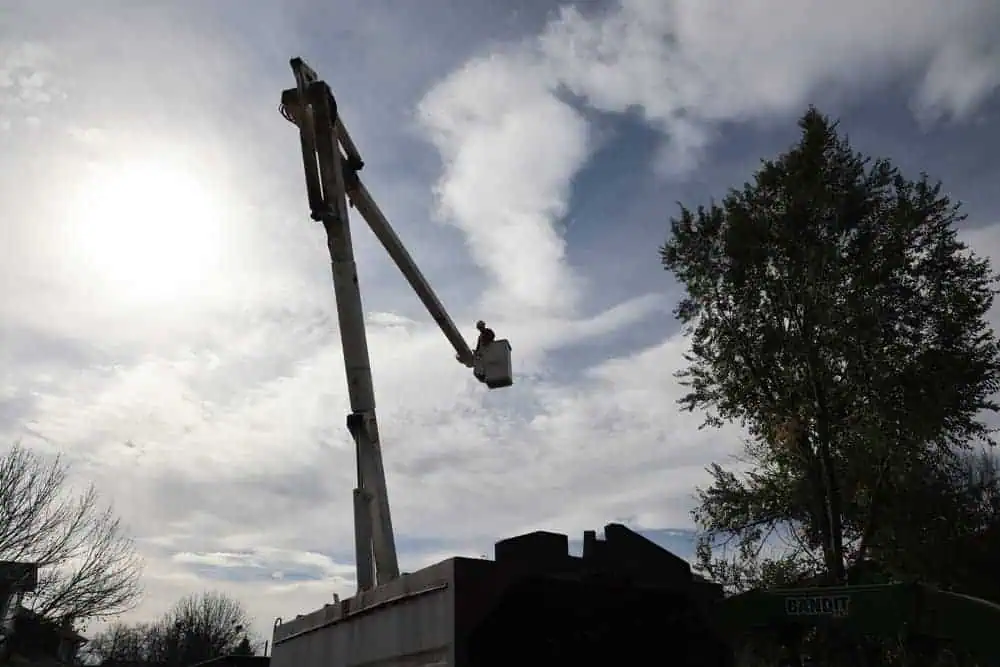 Bucket truck positioned for safe tree removal at property