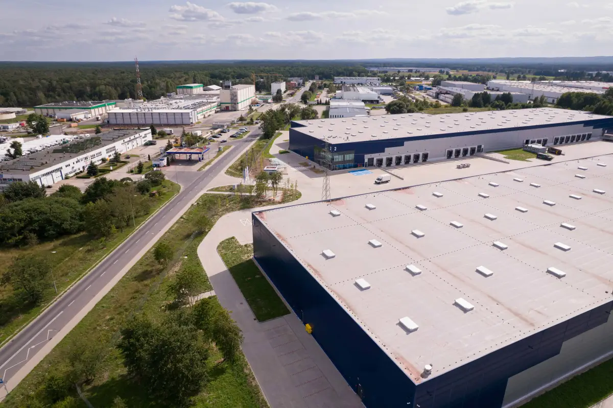 Aerial view of an industrial area with large warehouses surrounded by green trees, illustrating the proximity of nature to commercial spaces. Highlights potential areas for tree service and removal, relevant to Boulder Tree Service & Tree Removal Experts.