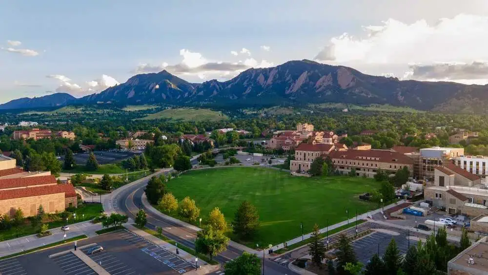 Aerial view of Boulder, Colorado, showing lush greenery and trees with the iconic Flatirons mountains in the background, highlighting the natural beauty and landscape suitable for tree services and care.