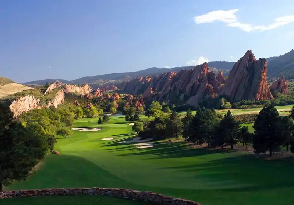 Scenic view of a lush green golf course surrounded by vibrant trees and red rock formations in Boulder, showcasing the natural beauty and tree care services of the area.